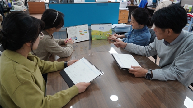 인천시사회서비스원 직원들이 안전 점검과 회계정보를 담은 2024년 탁상 달력을 보고 있다.
