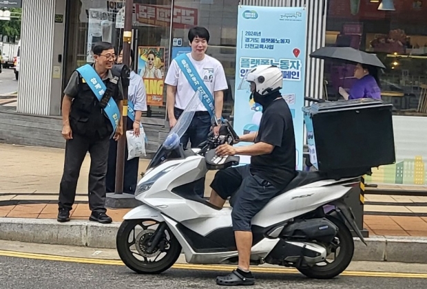 정차중인 배달라이더에게 안전용품 꾸러미를 전달하고 있다
